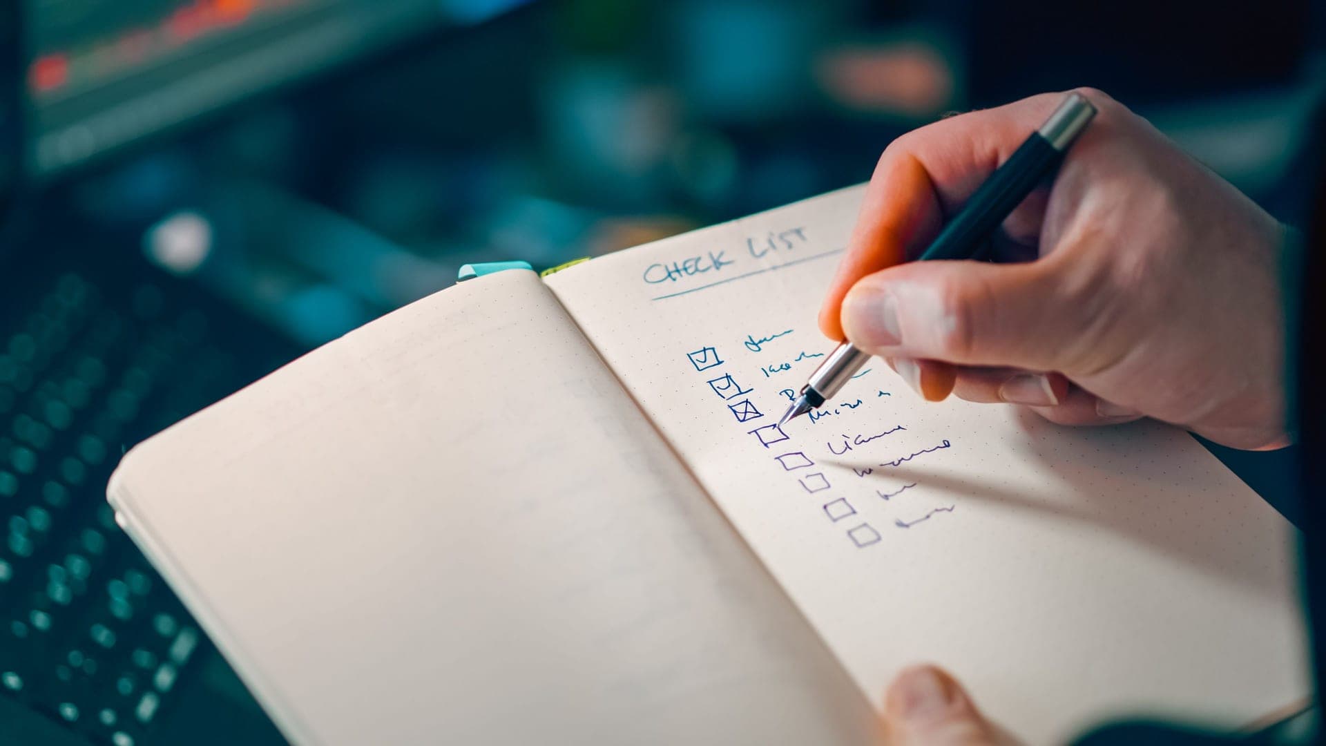 A hand writing a checklist in a notebook, close up
