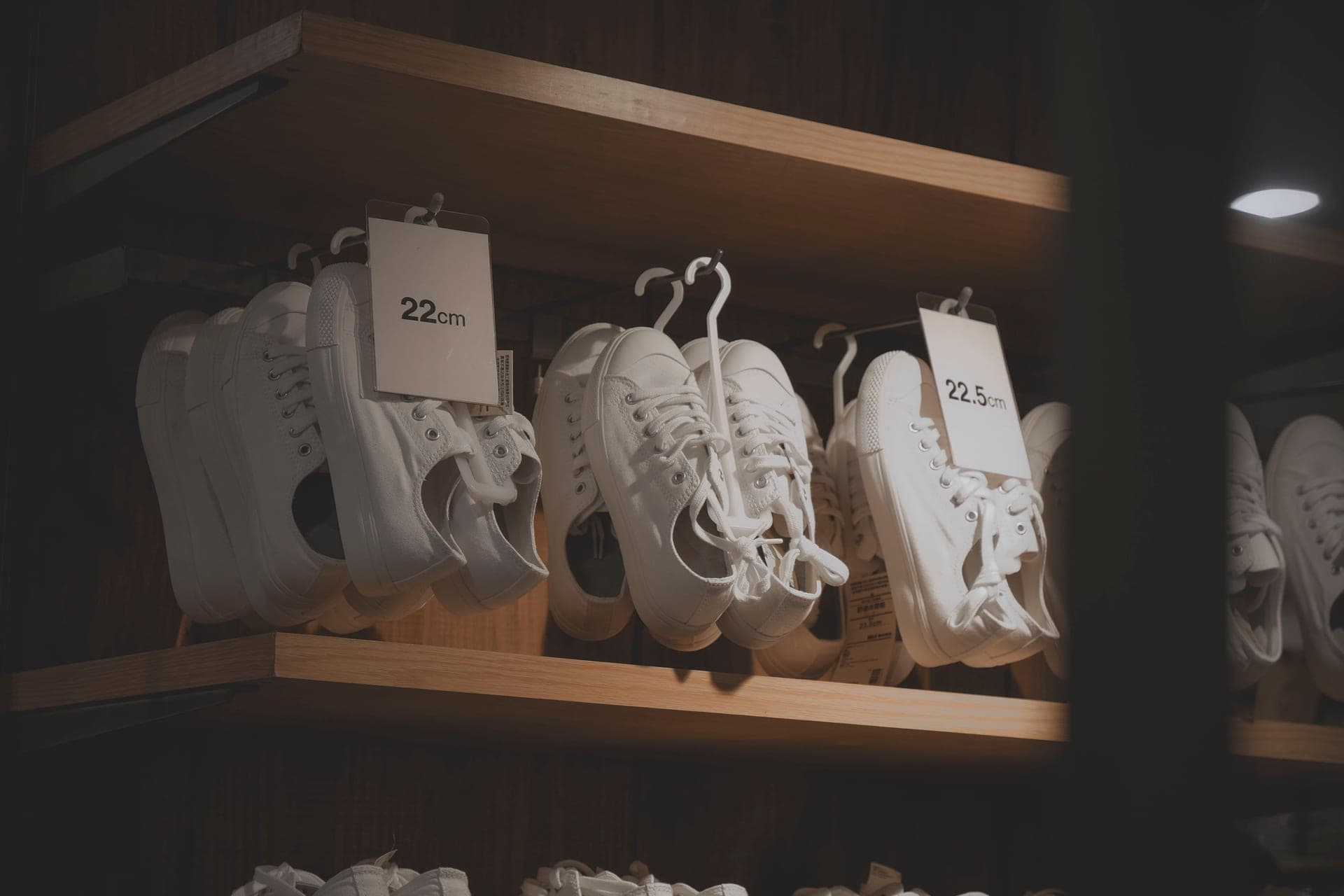 White low-top sneakers displayed on wooden shelves