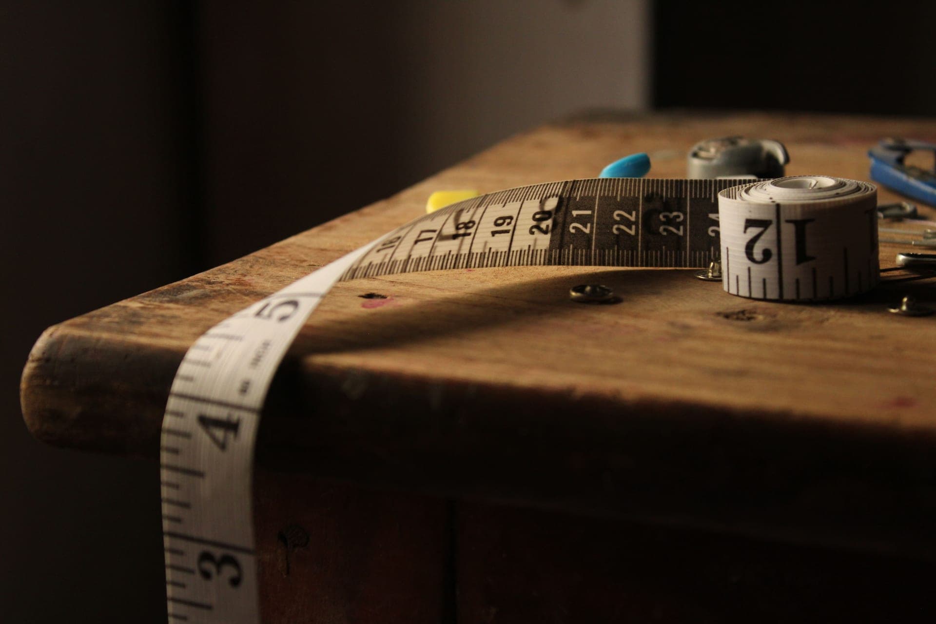 A rolled tape measure on a vintage wooden table in warm light